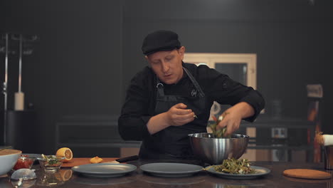 chef masculino aderezando ensalada, cocinando una receta gourmet de verduras frescas. cocinero profesional trabajando en la cocina.