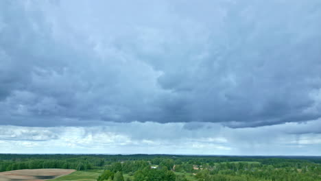 vista aérea de drones de nubes grises sobre el paisaje forestal rural de letonia con lluvia ligera en la distancia