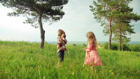 full length view of a caucasian little girl smiling and posing while her brother taking picture in the park on a sunny day