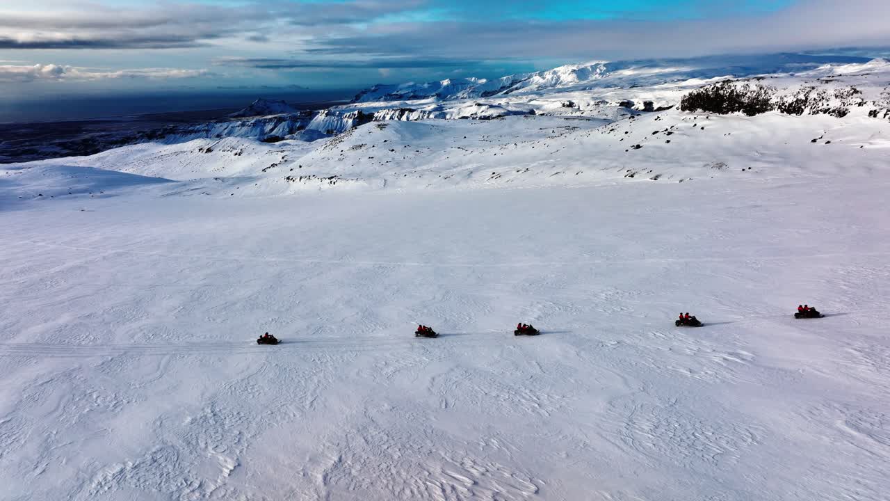 Aerial view of people riding snowmobiles on Myrdalsjokull glacier in Iceland, at dusk