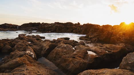 Vista-De-Lapso-De-Tiempo-Del-Atardecer-Desde-La-Costa-Rocosa,-Subida-Y-Bajada-Del-Agua-De-Mar-Con-La-Marea