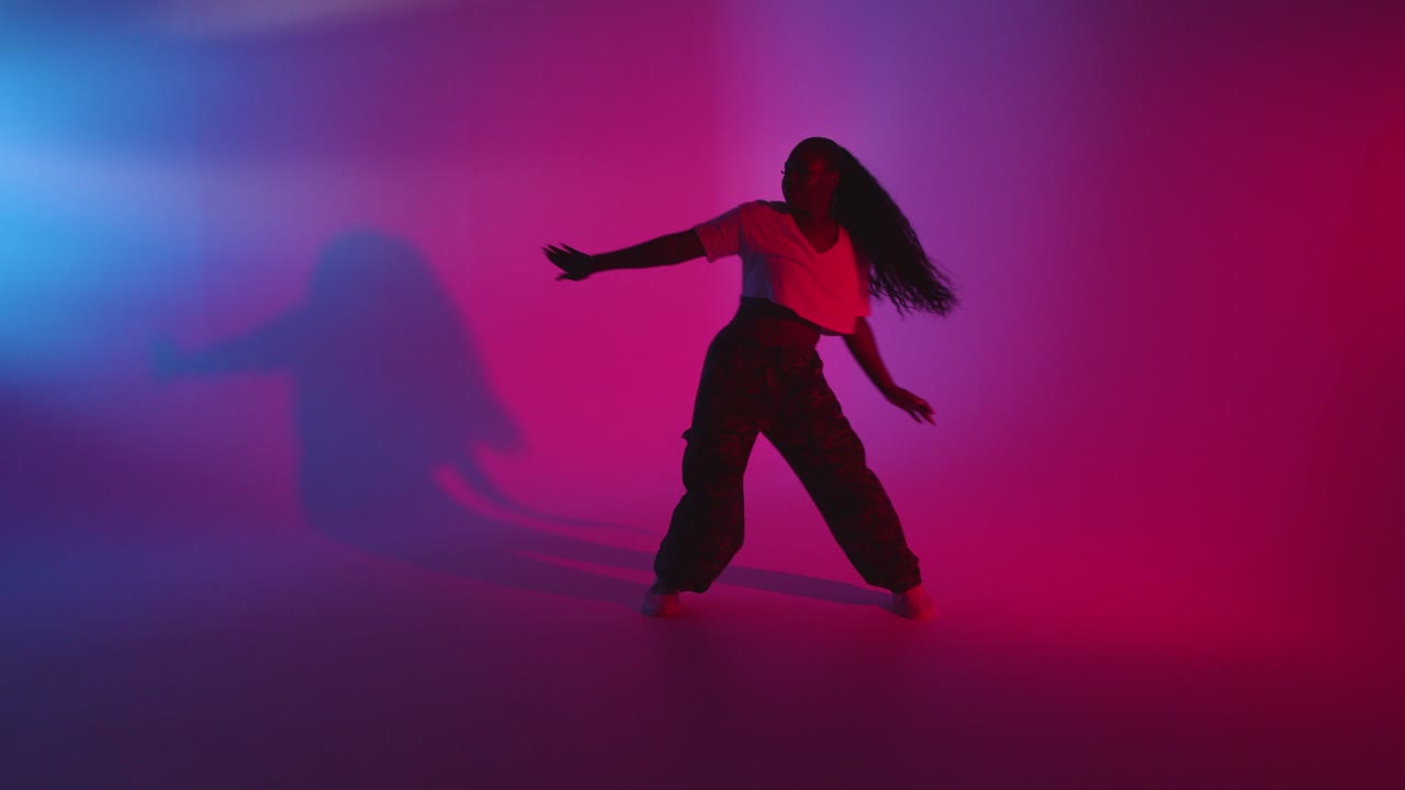 Full Length Studio Shot Of Young Woman Dancing Against Blue And Pink Lit Background 1