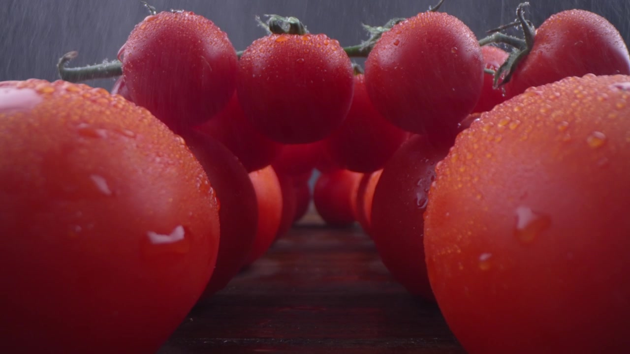 Wasser fällt auf frische rote Tomaten mit Wassertropfen