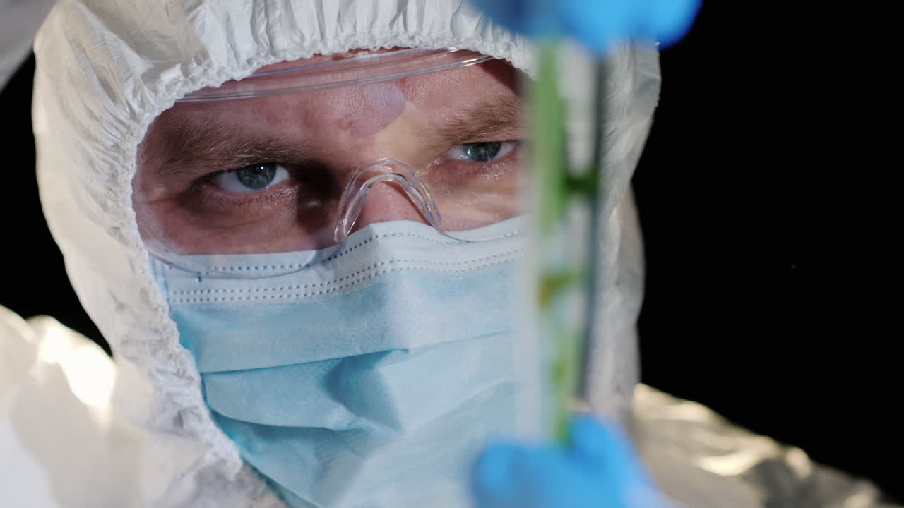 un investigador mirando de cerca un tubo de ensayo con una planta verde 1