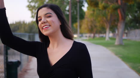 hermosa joven hispana independiente que se ve feliz mientras saluda a una amiga que se encuentra en el parque