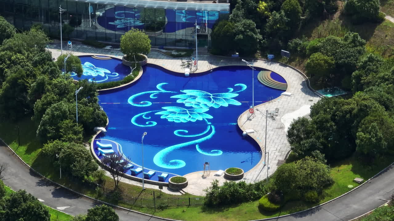 Telephoto drone shot circling a swimming pool decorated with flowers, sunny day