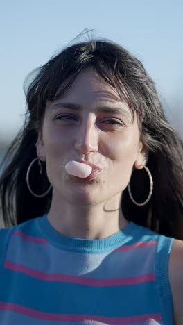 young woman blowing a bubble with chewing gum
