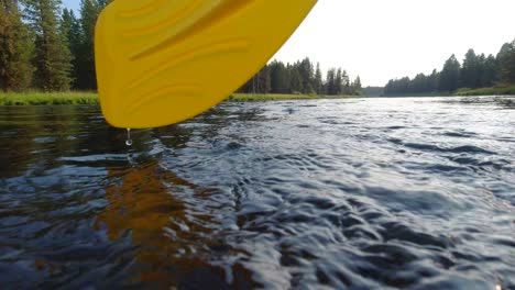 an oar from a river raft or boat crashing or splashing in on the water filmed at 60 frames per second or 60fps in a calm river in the idaho mountains as the water passes the camera