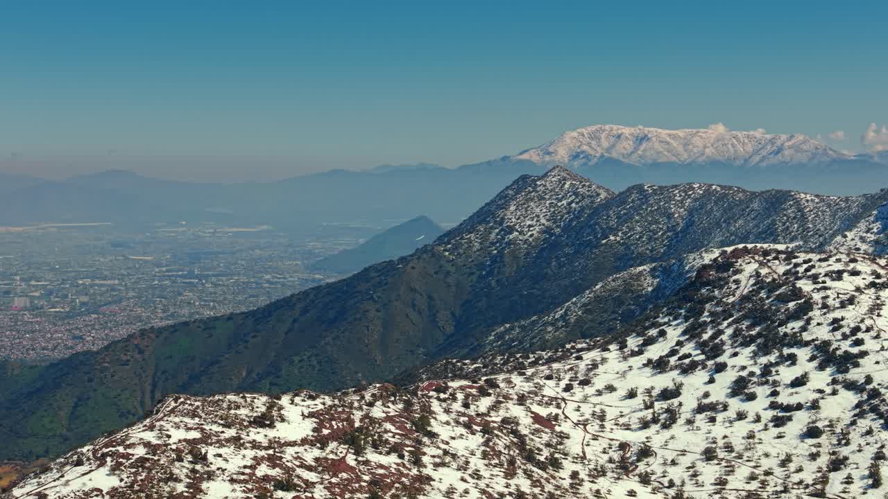 Fly over the snow-capped peaks of Mount Manquhue and Mount El Carbon in a light aircraft flying over the city of Santiago, Chile
