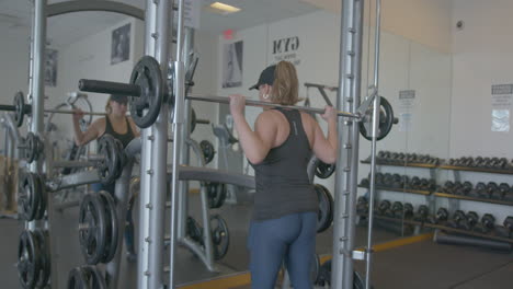 wide pan right of a woman doing barbell squats in slow motion