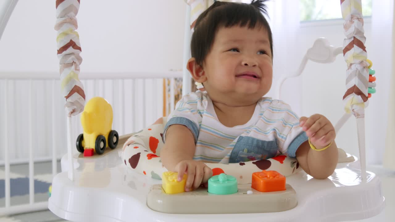 A joyful baby girl enjoys her time in a bouncy seat surrounded by toys and love.