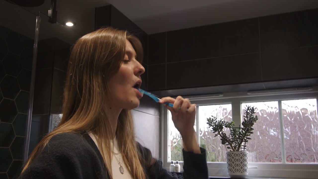 female model brushing teeth in a modern bathroom