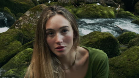woman in a green top by a mossy river