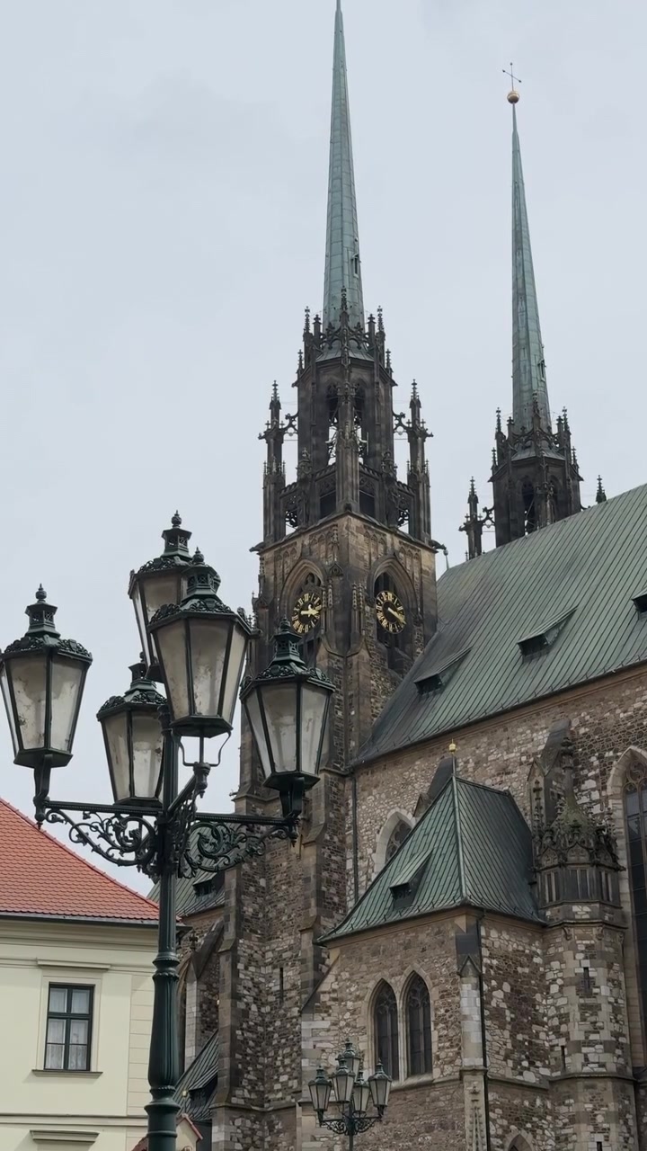 Video verticale 4K che cattura le iconiche guglie gemelle e la storica torre dell'orologio della Cattedrale dei Santi Pietro e Paolo contro il cielo a Brno.