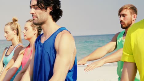 fit man and woman performing yoga at beach