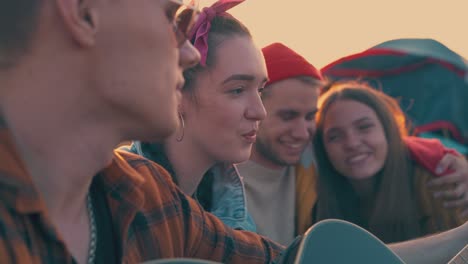 girl sings song to guitar resting with friends in camp