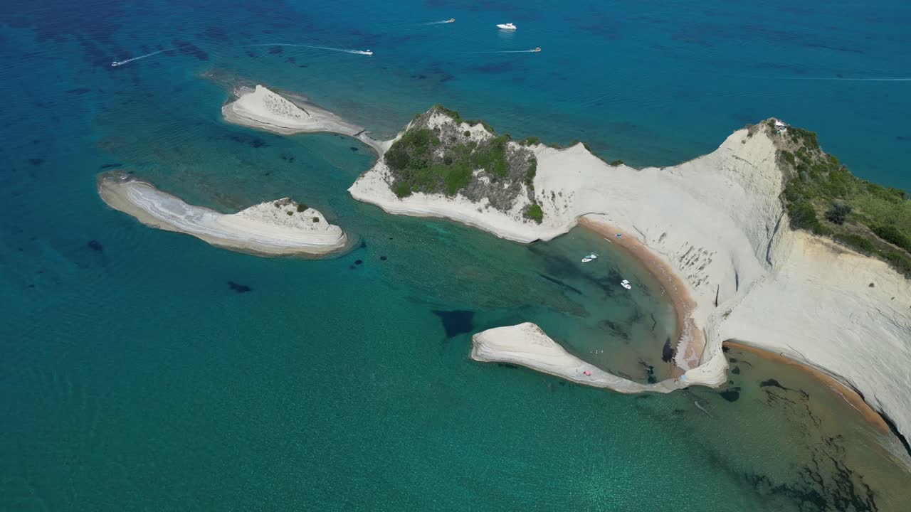 A drone captures the stunning white islands surrounded by crystal-clear water, revealing the visible seabed beneath, while boats gracefully cruise through the serene scene