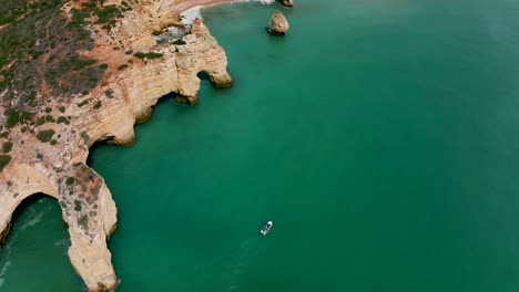 panorámica de imágenes de drones desde la costa del algarve mientras pasa una lancha a motor.