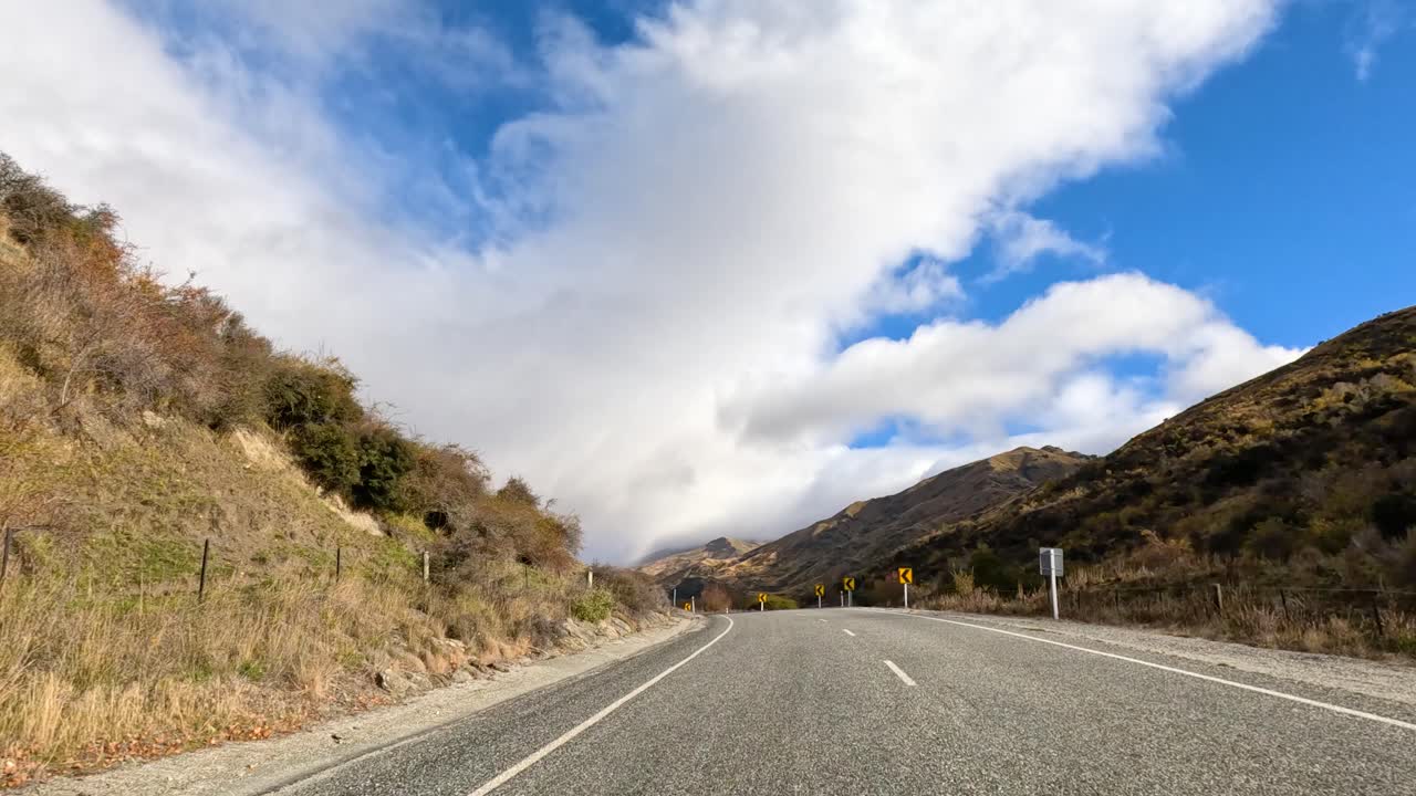 A 30-second drive through Wanaka's winding roads, showcasing stunning mountain views under a bright blue sky