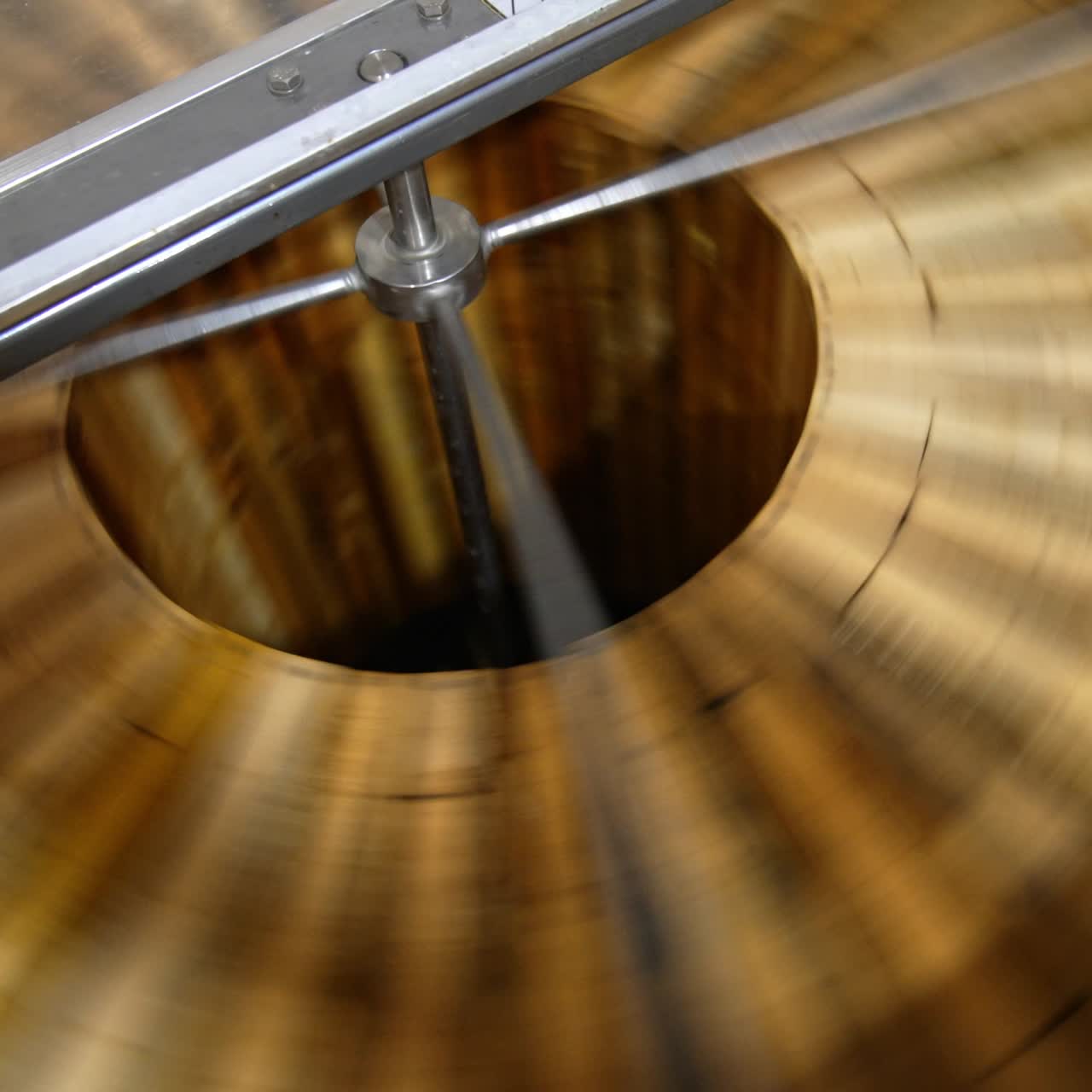 Fresh organic honey being extracted from wooden frames. Centrifuge machine rotating quickly for harvesting honey at apiary