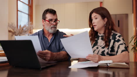 pareja discutiendo documentos financieros en casa