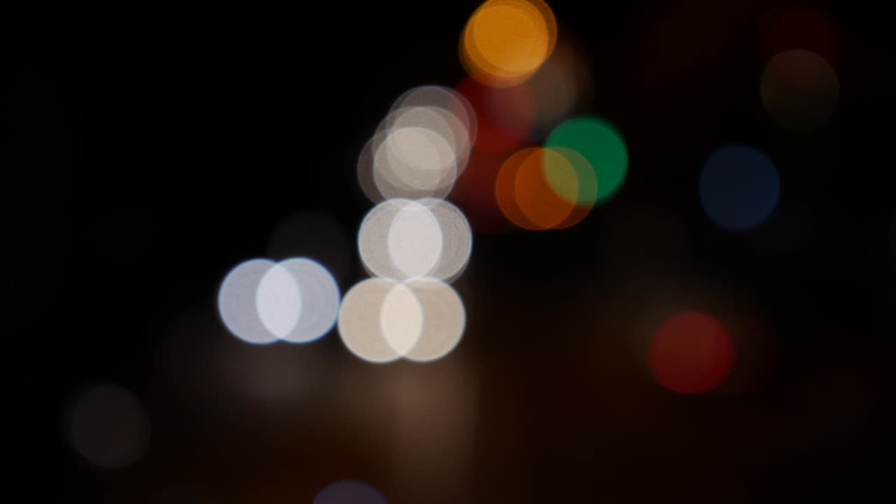 hermoso bokeh brillante en el fondo oscuro borroso por la noche. el redondo bokeh colorido brilla de las luces de los coches en la calle de la ciudad. fuera de foco con borroso. luces de la ciudad sin enfoque. bokeh de tráfico. concepto abstracto