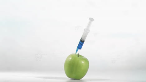 animación de una jeringa cayendo en una manzana verde contra un fondo gris.