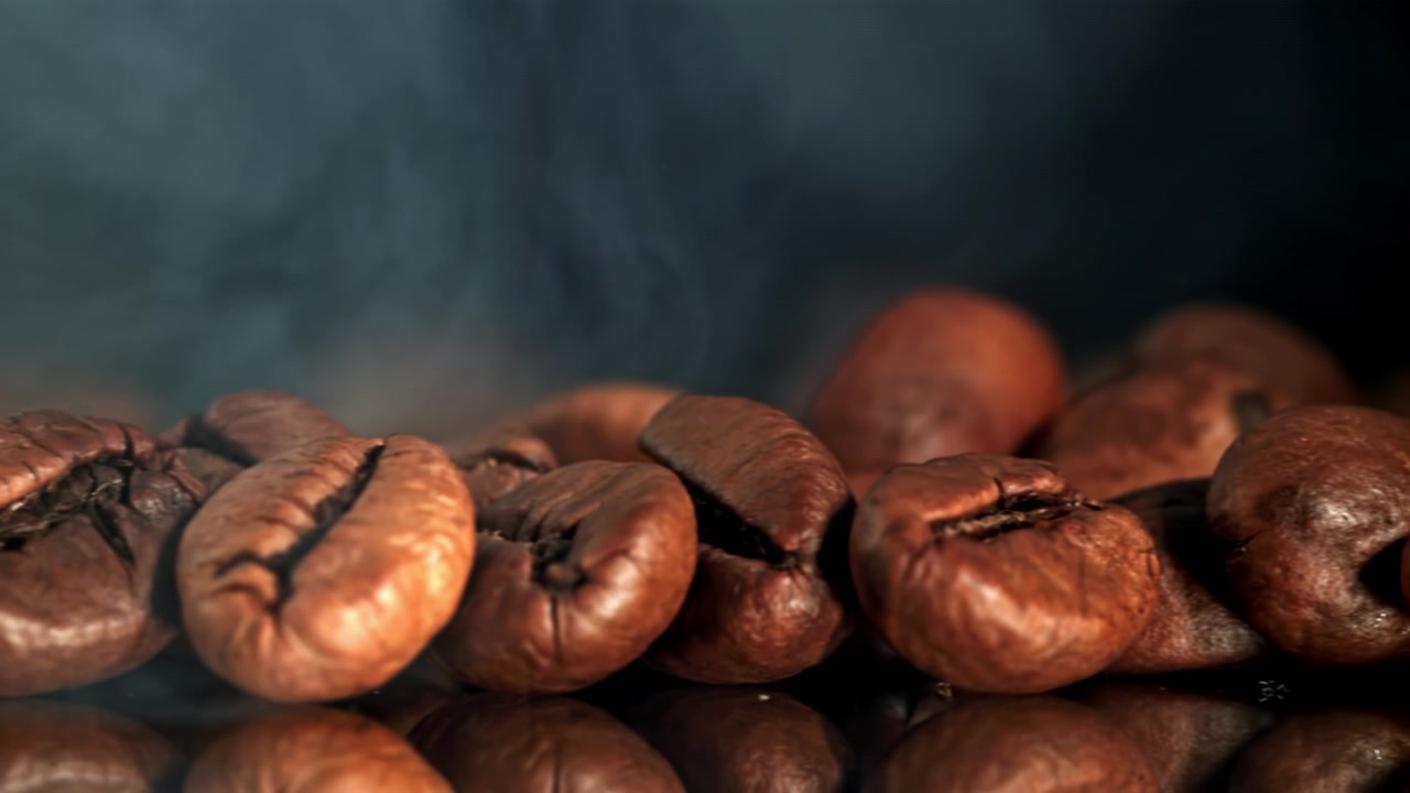 Nærbillede af dampende ristede kaffebønner med opstigende røg