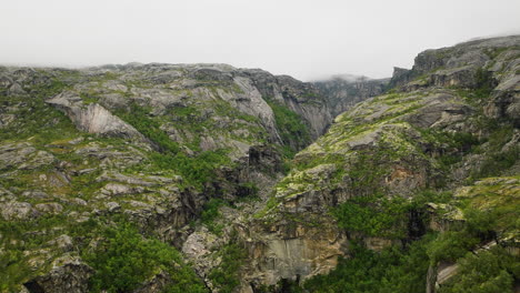 Falls-plunge-over-cliff-at-bottom-of-rugged-Hellmojuvet-canyon,-Norway