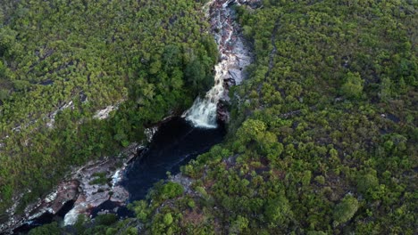 Toma-Aérea-Rotatoria-De-Drones-De-La-Impresionante-Cascada-Del-Pozo-Del-Diablo-Rodeada-De-Rocas-Y-Follaje-Selvático-En-El-Hermoso-Parque-Nacional-Chapada-Diamantina-En-El-Noreste-De-Brasil-En-Un-Día-Nublado