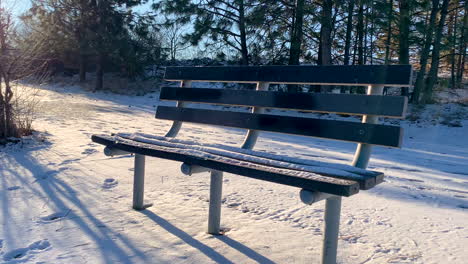 Tracking-shot-along-empty-bench-covered-in-snow
