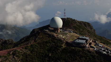 circular drone flight around the radar meteo station on one of the mountains of madeira with the clouds in the distance against the other mountain peaks