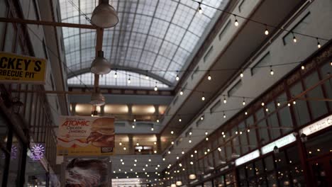 Interior-Del-Centro-Comercial-Con-Un-Enorme-Tragaluz-Suave,-Luces-De-Cadena-Y-Carteles-De-Comercio.