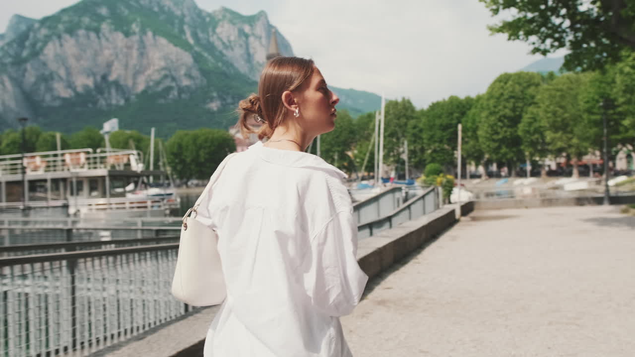 Young Woman Walking Along Lakeside Promenade with Scenic Mountain View