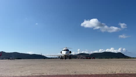 front view of a white color medium size bombardier crk jet parking in ibiza’s airport, spain, in a splendid spring day