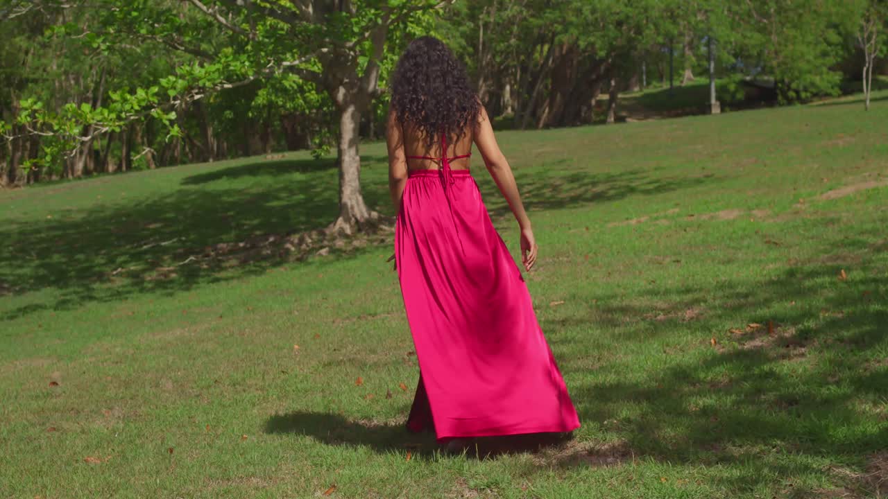 молодая латиноамериканка наслаждается тропическим карибским парком, ее красное платье вращается, когда она движется