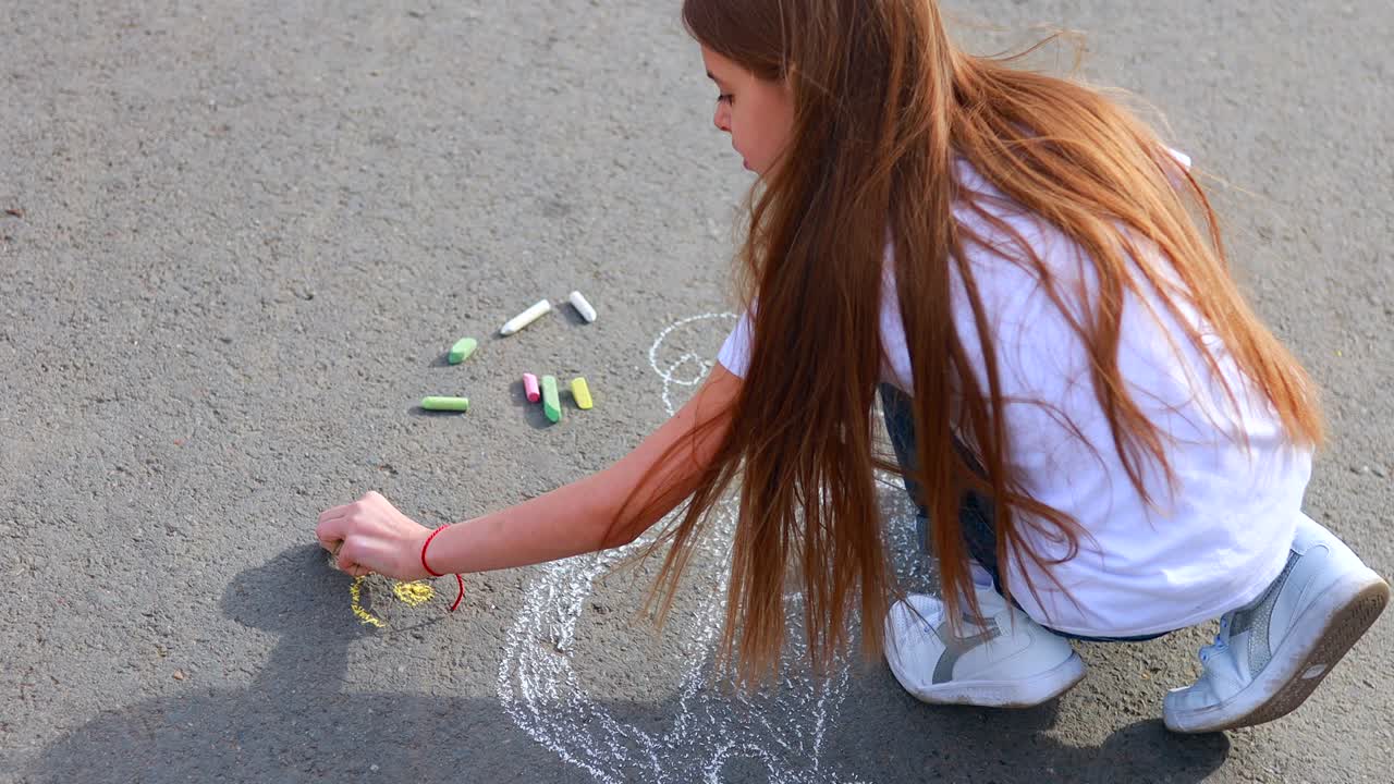Liten jente med kreativ hobby tegner en elbil på asfalten med kritt, med fokus på miljøvennlighet og energisparing, i en park en sommerdag