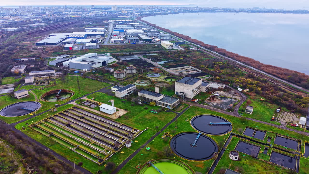 Views of an industrial area near a body of water surrounded by several buildings and facilities during daytime