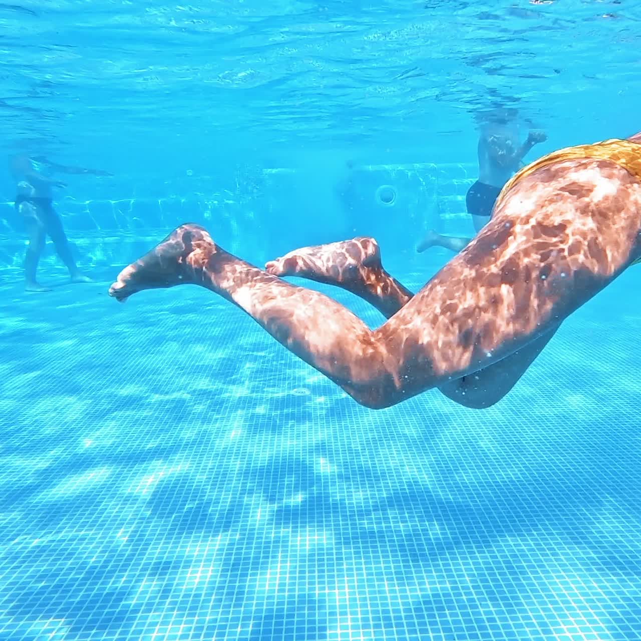 Giovane donna che nuota sott'acqua in piscina