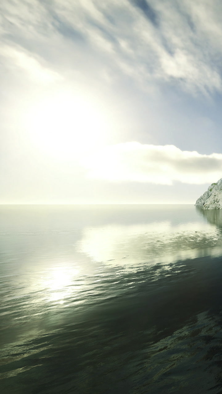 Sunlight reflects on calm water near rocky coast during early morning