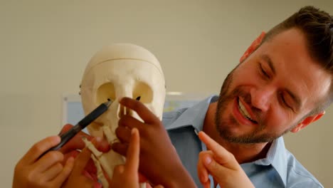 caucasian male teacher fixing human skeleton model in classroom at school 4k