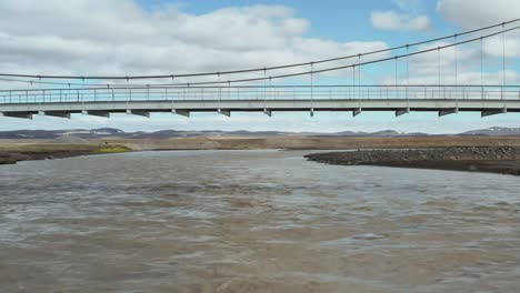 Fliegen-Unter-Hängender-Hängebrücke-Am-Gletscherfluss-In-Island,-Antenne