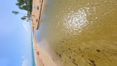 Vertical-drone-flight-over-sand-and-river-with-playing-kids-flowing-into-Caribbean-Sea-during-sunny-day