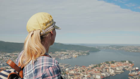 a woman tourist admires a beautiful view of the city of bergen in norway tourism in scandinavia conc