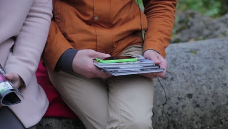 couple sitting outdoors holding photo albums and phones