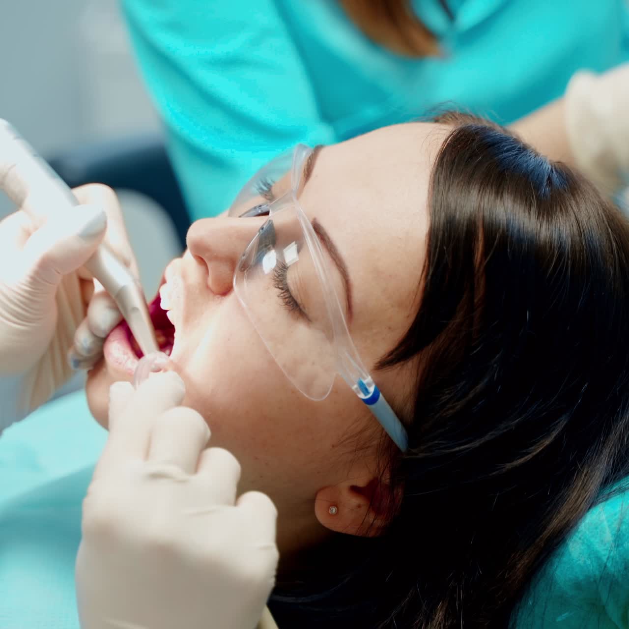 Woman patient with opened mouth at stomatology clinic. Professional dentist treating teeth using medical equipment. Close-up.