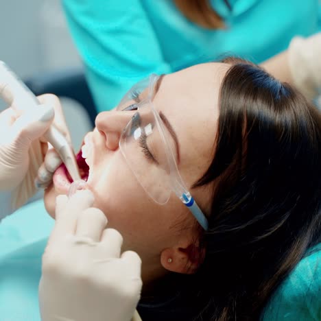 woman patient with opened mouth at stomatology clinic. professional dentist treating teeth using medical equipment. close-up.