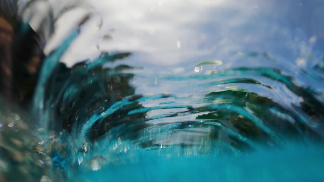 Filmato di un tubo di bolle sott'acqua in una piscina che crea increspature e immagini distorte