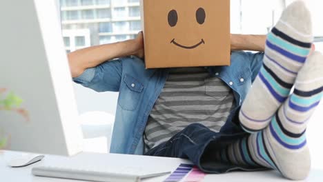 photo editor wearing smiley face box on his head