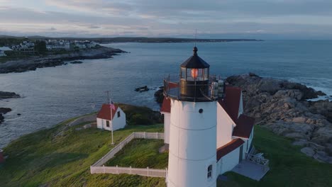 aerial drone shot of york beach maine flying around cape neddick nubble lighthouse at sunset